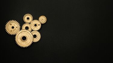 A series of gold cogs on a black background 
