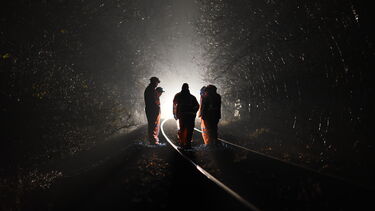 Moody shot of engineers on a railway line at night