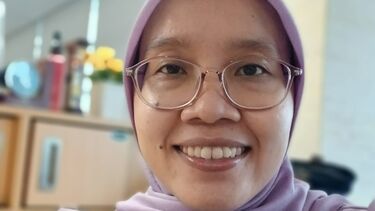 Anis Apriliawati in glasses and headscarf smiling at the camera