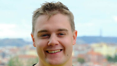 Student Jack Roberts smiling at the camera with a blurred city backdrop