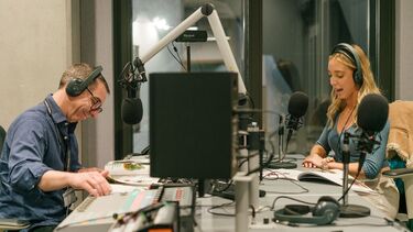 Two people sitting opposite each other using recording equipment