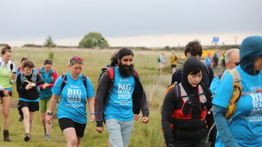 A group of walkers, wearing the big walk t-shirts and walking in the peaks