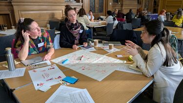 Colleagues sat around a table with paper and pens in front of them 