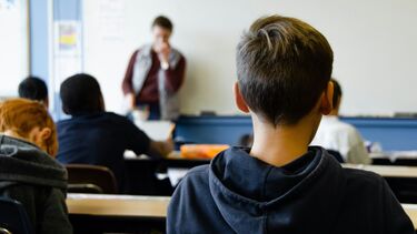 Photograph of pupils in a classroom with the teacher stood at the white board