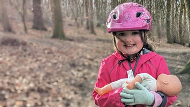 Zoe is a 5 year old girl, she wears a bicycle helmet and plays in the woods