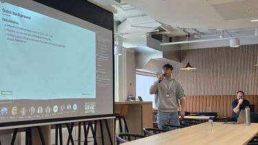 A person speaking into a microphone whilst delivering an in-person presentation