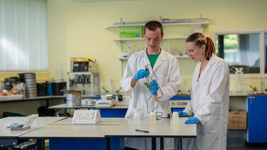 Students analysing water samples collected in the field using a pH meter.