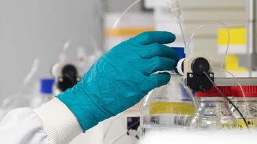A gloved hand holding a beaker with chemicals in it