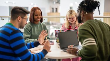  A group of students in discussion around the table.