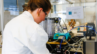 A researcher wearing a white lab coat setting up an experiment