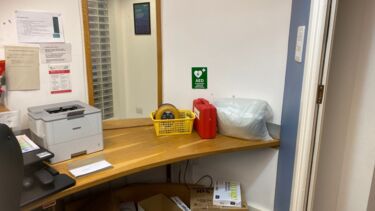 A defibrillator in a yellow basket on a desk