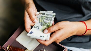 A close up of a young person's hand holding a number of Euros notes.