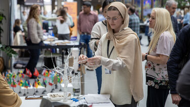 A person ties a label onto a model tree
