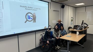 Disability Matters team next to presentation slide