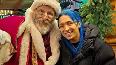 Student with blue hair standing with Santa