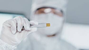 A fabrication engineer holding a small semiconductor sensor