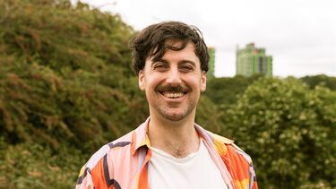 Man standing in green space looking at camera smiling 