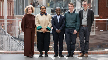 Five colleagues from the Universities of Sheffield and Cape Town stand on a mezzannine floor in a row and smile towards the camera.