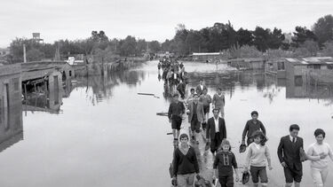 A line of people walking away from a flooded town