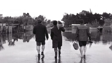 Three people walking through floodwater
