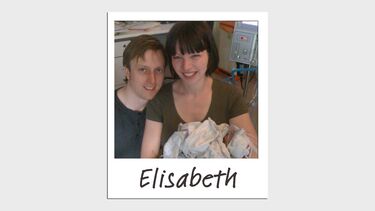 A man and woman smiling holding a newborn baby