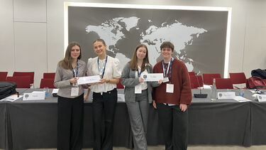 Four students holding placards of their assigned country