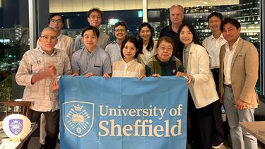 A group of people holding a blue University of Sheffield banner