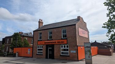 Two storey red brick house with signage for Henderson's Relish on the front and side