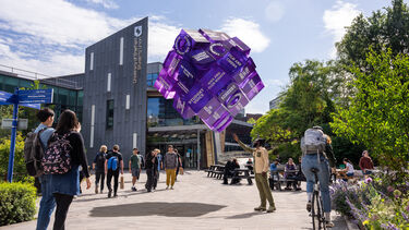 Students next to Sheffield Students' Union and looking at a purple cube