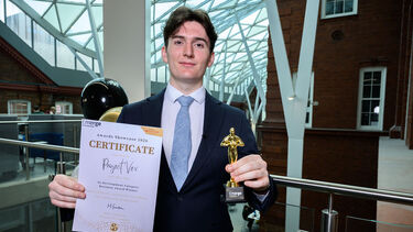 Man standing with certificate and trophy 