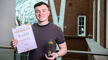 Man standing with trophie in the heartspace looking at camera and smiling 