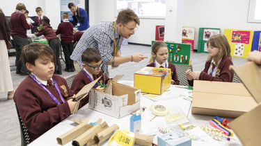 Primary school children doing arts and crafts around a table to learn about fusion energy