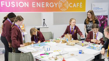 Primary school children doing arts and crafts around a table to learn about fusion energy
