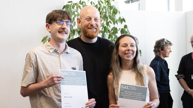 Two students smiling showing their certificates with employer sponsor