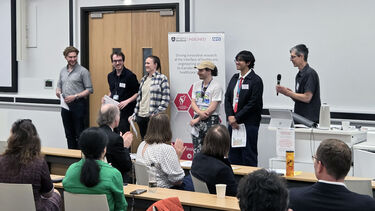 Six people accepting poster prize certificates and standing in front of an applauding audience