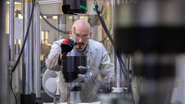 Technician loading a new polymer composite sample into a mechanical testing rig