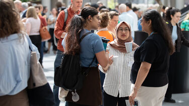 A group of three women talking amongst a crowd of people