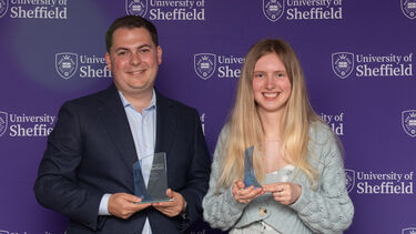 Two people smiling and holding awards
