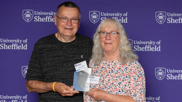 Two people smiling and holding awards