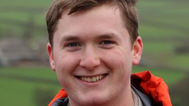 Profile of an engineer in a high vis jacket smiling
