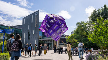 Students next to Sheffield Students' Union and looking at a purple cube