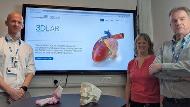 Two men and a woman standing either side of a large screen displaying the 3DLab website.