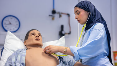 Medical student using a stethoscope on a test dummy