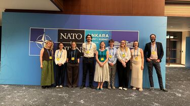 Eight students standing in front of the NATO Ankara sign