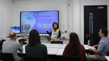 A mandarin class in session. Teacher and students and screen.