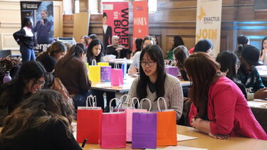 Women talking around table in Mappin Hall with banners 