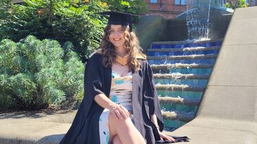 Women sitting with graduate gown in Sheffield peace gardens