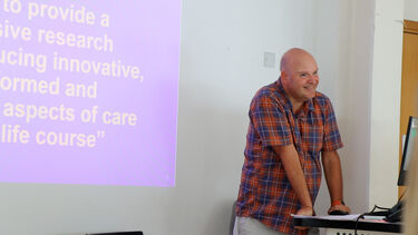 Professor Liam Foster stands at a lecturn in front of a presentation