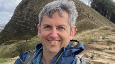 Engineer standing in front of a hill smiling