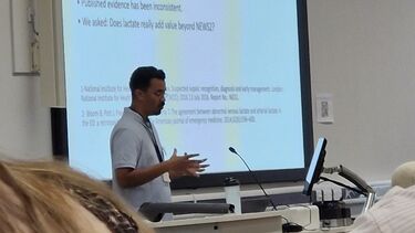 Yazeed stands in front of a slide from his presentation